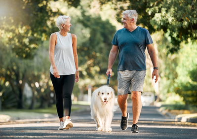 older couple walking dog outside