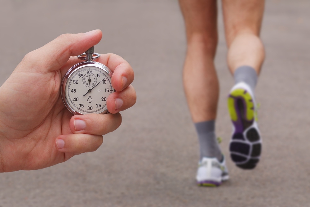 hand holding stopwatch timing person running